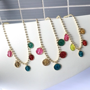 Detail of four gold bead bracelets with colorful oval religious medal charms in enamel