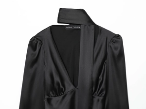 Macro shot of V-neckline on black satin blouse with tie detail and size S label