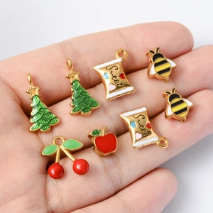 Hand holding assorted Christmas enamel charms including trees, apples, and cherries