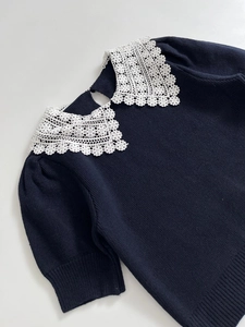 Detail of white crochet lace collar on navy blue knit sweater with water-drop back opening