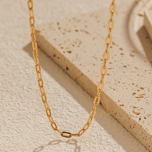 Collar minimalista de cadena de clip bañado en oro 18K sobre fondo de piedra