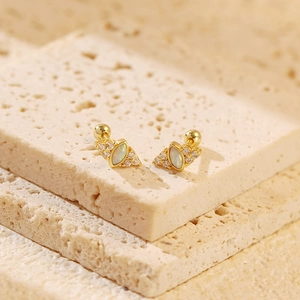 Detailed shot of gold S925 opal stud earrings with screw backs on travertine stone