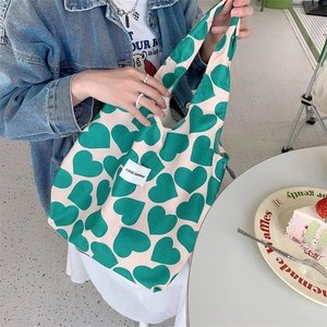 Detailed close-up of corduroy tote bag with green hearts and LOVE SOZAKKA woven label