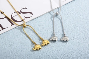 Detailed view of adjustable gold and silver elephant pendant necklaces on a blue texture