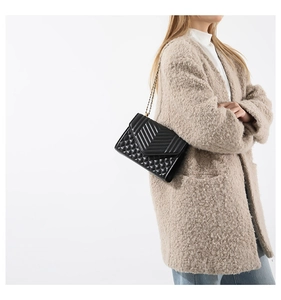 Detail of a black quilted shoulder bag with V-shaped stitching and golden metal chain strap