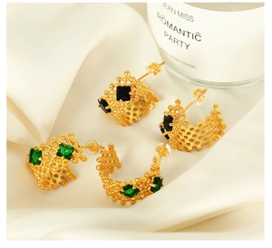 Détail de boucles d'oreilles en treillis doré avec zircons carrés noirs et verts sertis