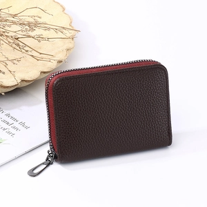 Detail of dark brown lychee leather card holder with red zipper tape on white background
