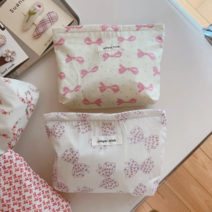 Flat lay of pink bow fabric makeup bags with simple wish labels on a white surface