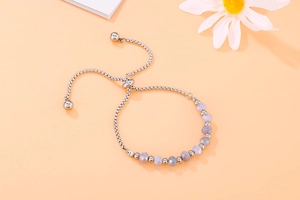 Detail of beaded steel bracelet featuring faceted purple stones and adjustable slider clasp