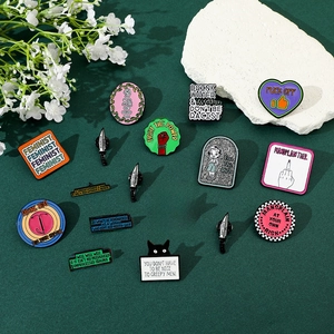 Feminist enamel pin set with colorful daggers and hearts on green fabric backdrop