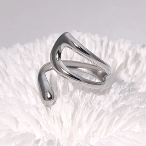 Adjustable silver irregular fluid ring in stainless steel on a white artistic base