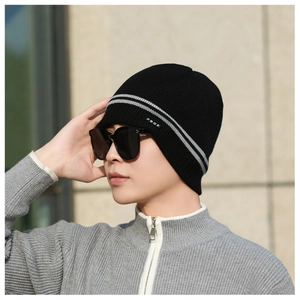 Close-up of a black winter knit beanie featuring grey stripes and a small brand logo tag