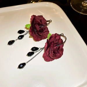 Close-up of deep red velvet rose earrings with hanging black teardrop beads and chains