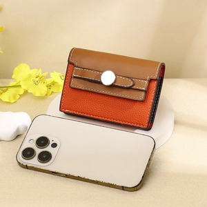 Brown and orange leather card holder with lychee grain texture shown next to a phone