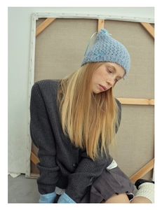 Detail view of light blue knit cat ear hat with bow and grey cardigan outfit