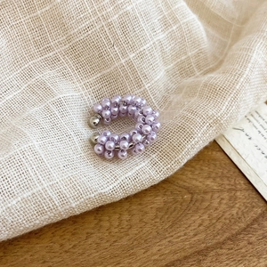 Close-up of elegant purple beaded ear cuff on beige fabric and wooden background