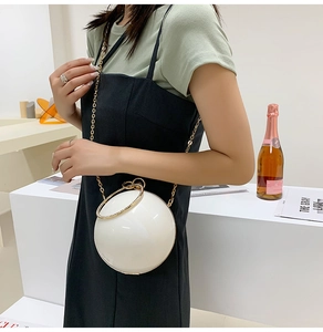 Detail of white acrylic sphere evening bag with gold ring handle and chain strap