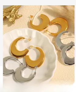 Detailed macro of gold and silver moon-shaped hoop earrings on a decorative ceramic tray