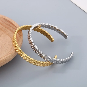 Detail of twisted cable texture on gold and silver stainless steel C-shaped open bangles