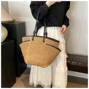 Close-up of large straw tote bag with black leather handles and trim for summer style