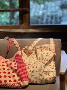 Detail of red polka dot and dog print canvas tote bags on a gray armchair