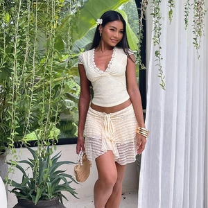 Dettaglio del tessuto in pizzo bianco sporco su top con scollo a V e gonna a balze