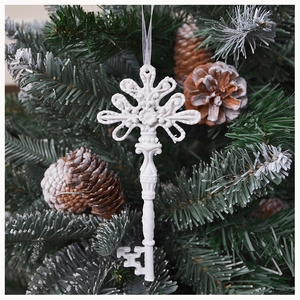 White vintage resin key ornament with intricate carvings hanging on a Christmas tree