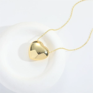 Minimalist polished gold heart pendant necklace on a clean white modern circular base