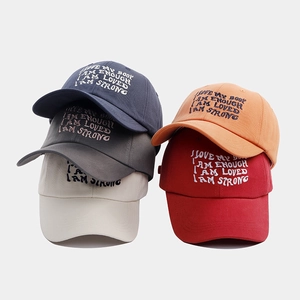Detail of five colorful baseball caps with embroidered motivational phrases and soft fabric