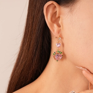 Detail shot of heart-shaped pink zircon drop earrings worn on a female model