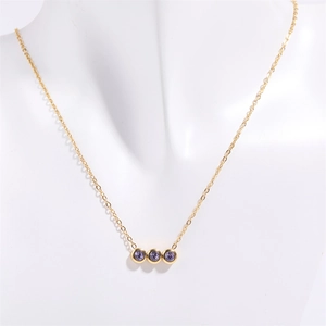 Détail du collier doré avec trois pierres violettes serties sur une fine chaîne en or