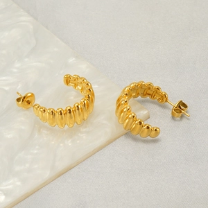 Vue détaillée des boucles d'oreilles créoles en acier doré à texture gaufrée élégante