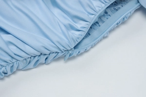 Dettaglio dell'abito azzurro con inserti in pizzo e chiusura a cerniera invisibile
