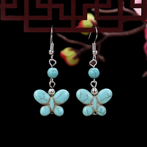 Detail of vintage turquoise butterfly earrings with antique silver finish and boho accents