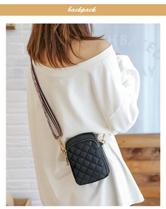 Close-up of black quilted nylon bag with colorful woven strap and gold zipper detail