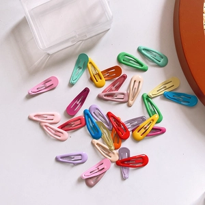 Assorted colorful candy-colored metal BB hair clips scattered near a plastic storage box