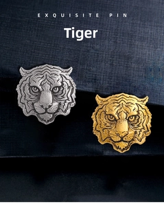 Detailed relief of tiger head brooches in gold and silver finish on textured blue background