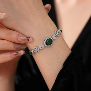 Close-up of a vintage silver bracelet with an emerald green oval stone and zircon floral links