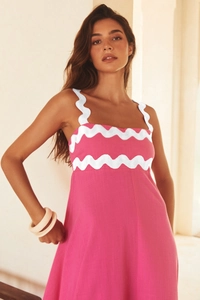 Detail of rose pink linen dress featuring white ric-rac trim and high-quality fabric texture