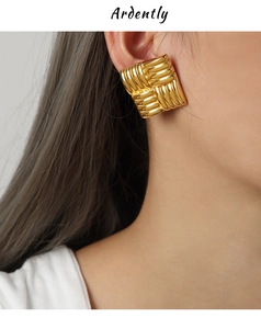 Close-up of gold square earrings featuring a bold crisscross woven metal texture