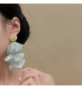 Detail of mint green chiffon petal earrings with textured golden studs on model