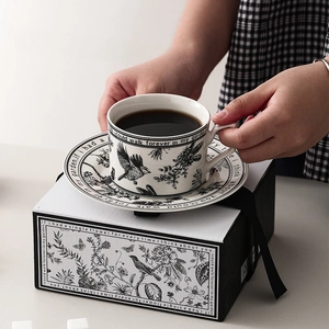 Elegant black and white ceramic coffee cup and saucer set with floral bird illustrations
