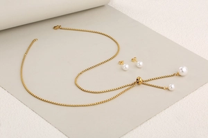 Detailed view of adjustable pearl necklace and matching stud earrings set in gold