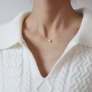 Macro shot of single natural pearl pendant on a transparent fishing line necklace
