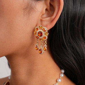 Macro shot of vintage gold drop earrings with amber gemstones and crystals worn by a model