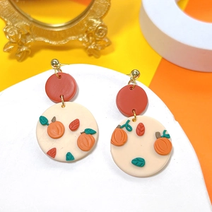 Detail view of handmade Halloween clay earrings featuring pumpkin and leaf motifs