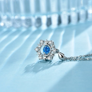 Macro detail of snowflake necklace with central blue gemstone and pavé sparkling diamonds