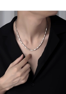 Detail of silver stainless steel geometric link chain worn on a black shirt neck