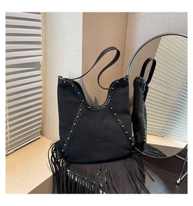 Detail of black bohemian tassel bag with sun relief, silver rivets, and leather fringes