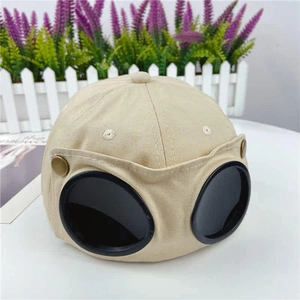 Detail of khaki cotton baseball cap featuring integrated black pilot goggles and brass studs